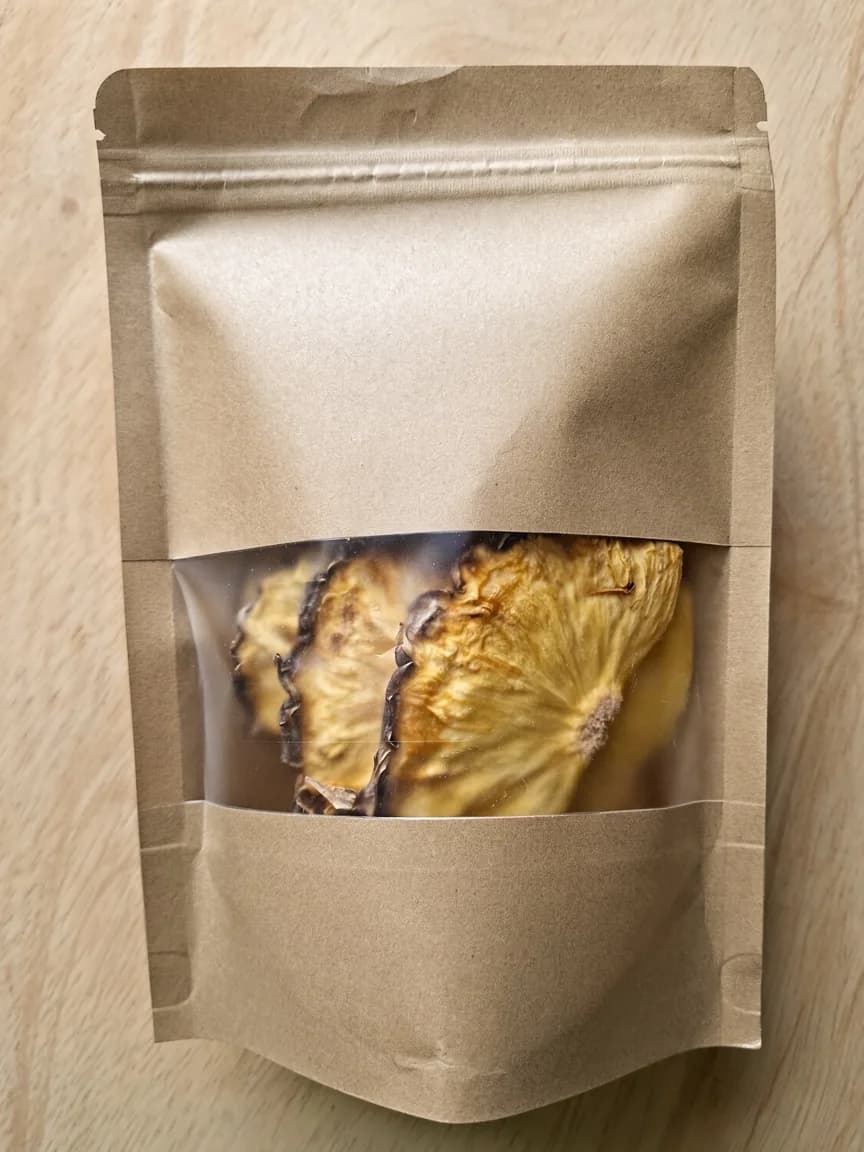 Sachet kraft laissant voir des demi-tranches d’ananas séchées.